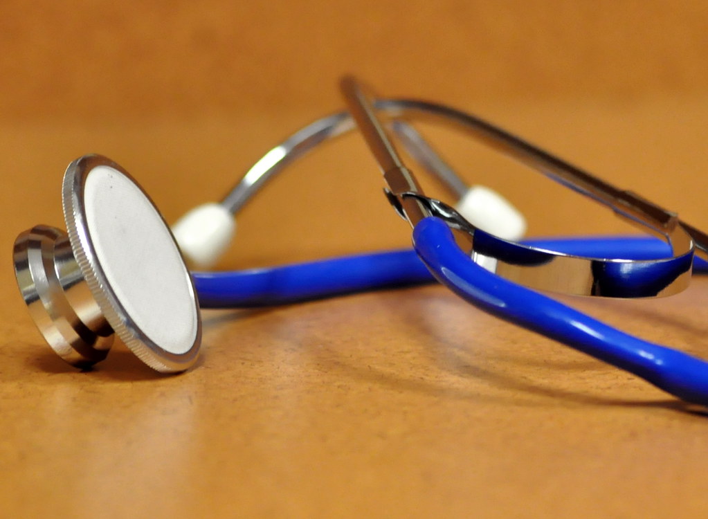 Blue stethoscope on a wooden table.