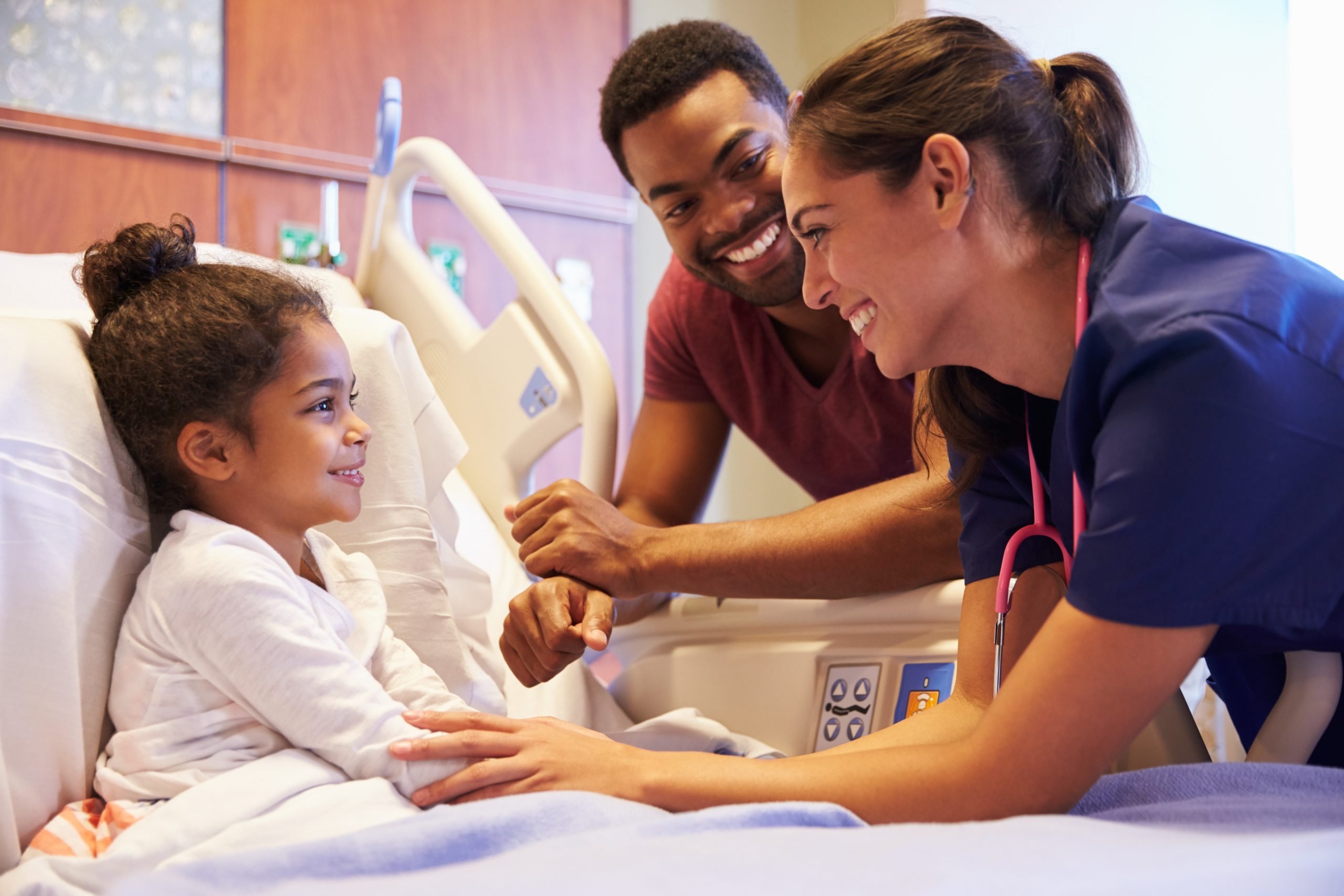 Child who is about to be sedated looks happy while on the bed, surrounded by trusted people.